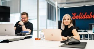 Kuvituskuva: Solidabiksen työntekijät Sara ja Veli-Pekka Solidabiksen toimistolla työskentelemässä.