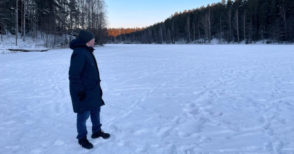 Kuvituskuva: Ohjelmistokehittäjä Henri Lehtinen kävelemässä jäätyneen järven päällä lumisessa maisemassa.